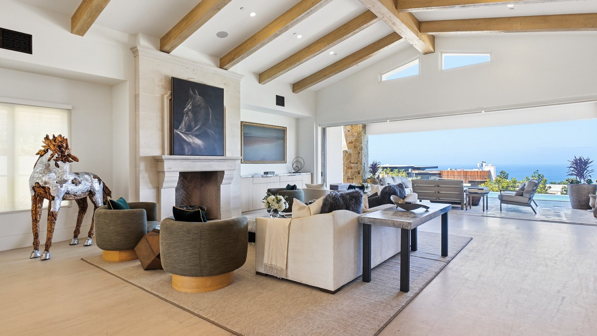 The great room fireplace, with the ocean visible through the open glass wall.