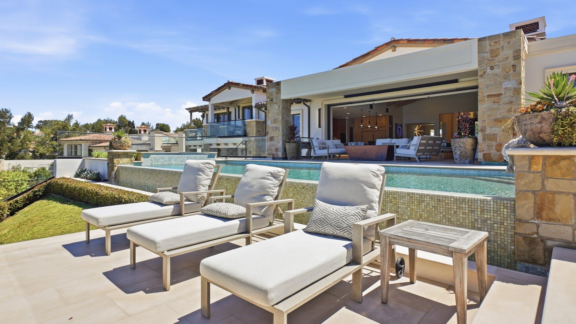 The pool deck with loungers, looking back at the house.