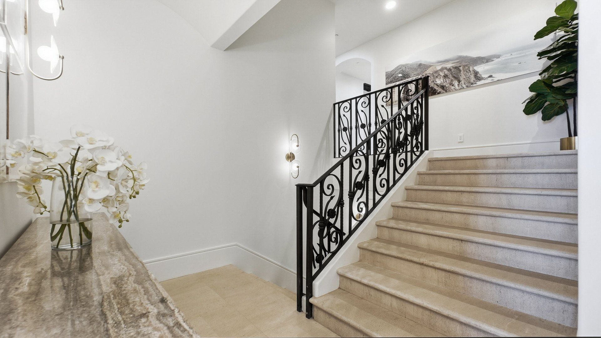 The foyer and stair, with wrought iron rail and orchids.