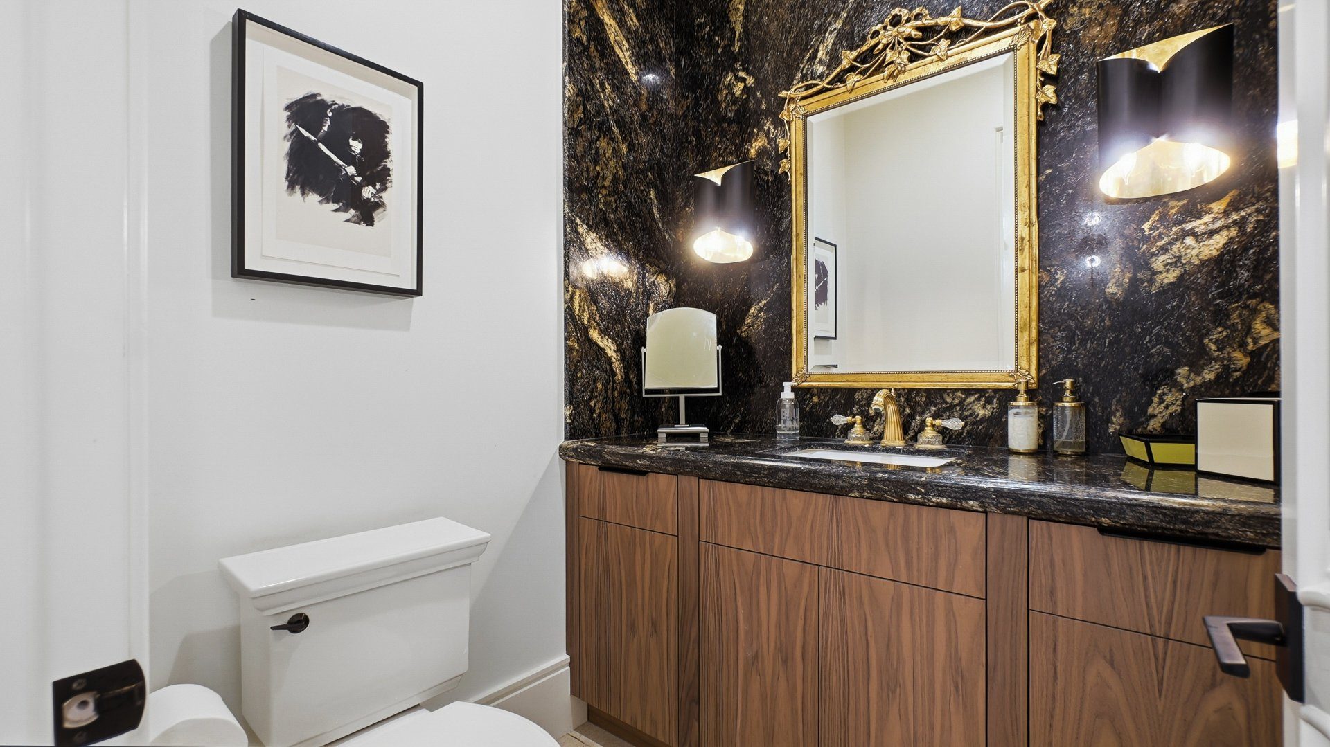 The powder room, in dark stone with a gilt mirror.