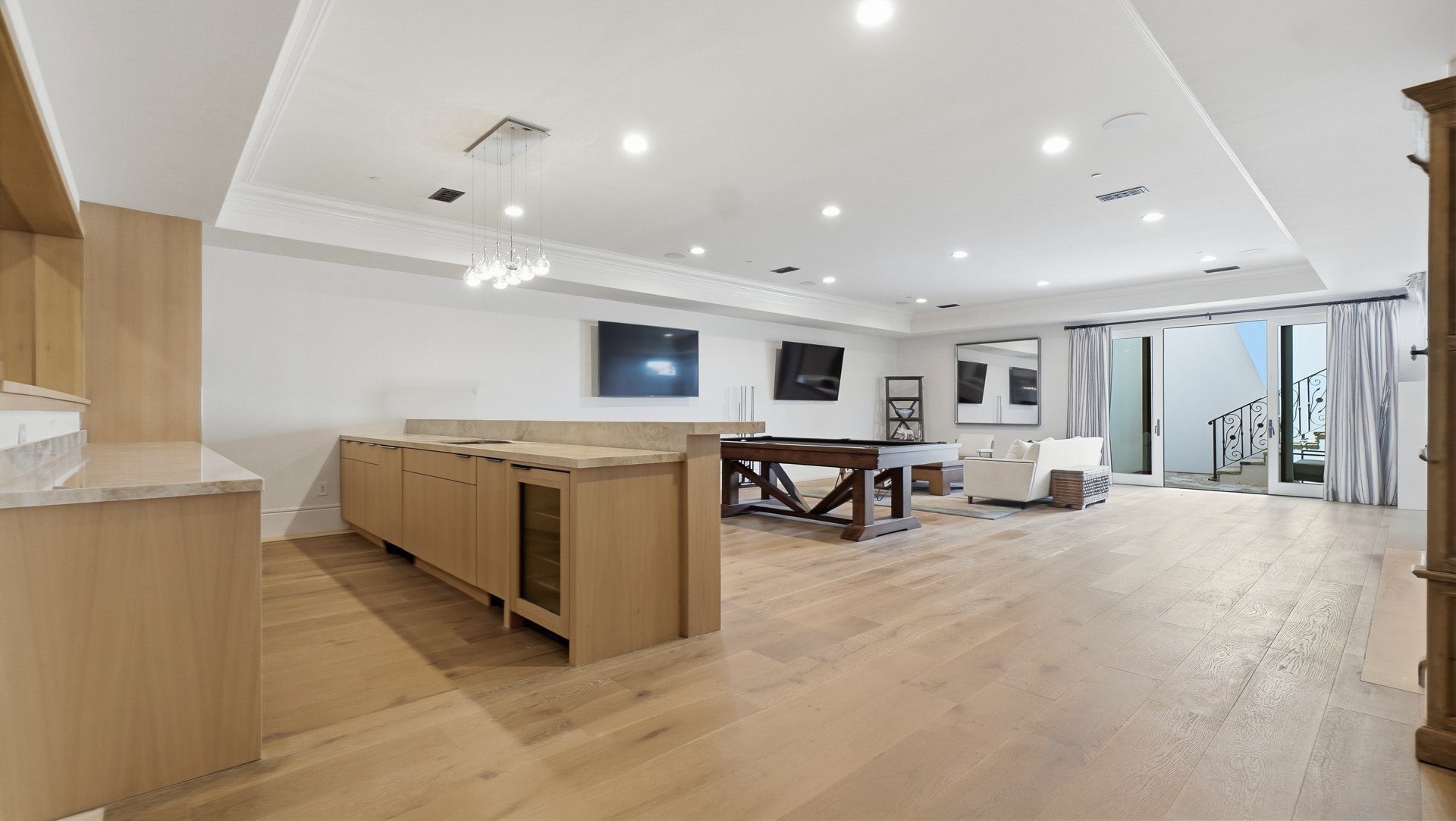 The game room with a billiards table, bar and lounge seating.