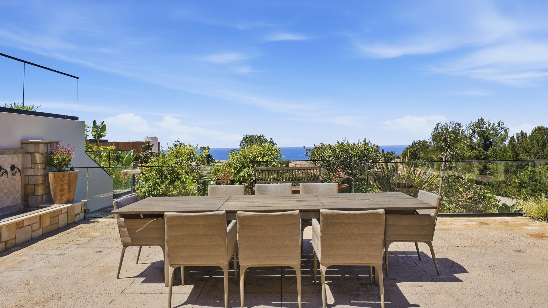 The dining terrace with a long table and the ocean beyond.