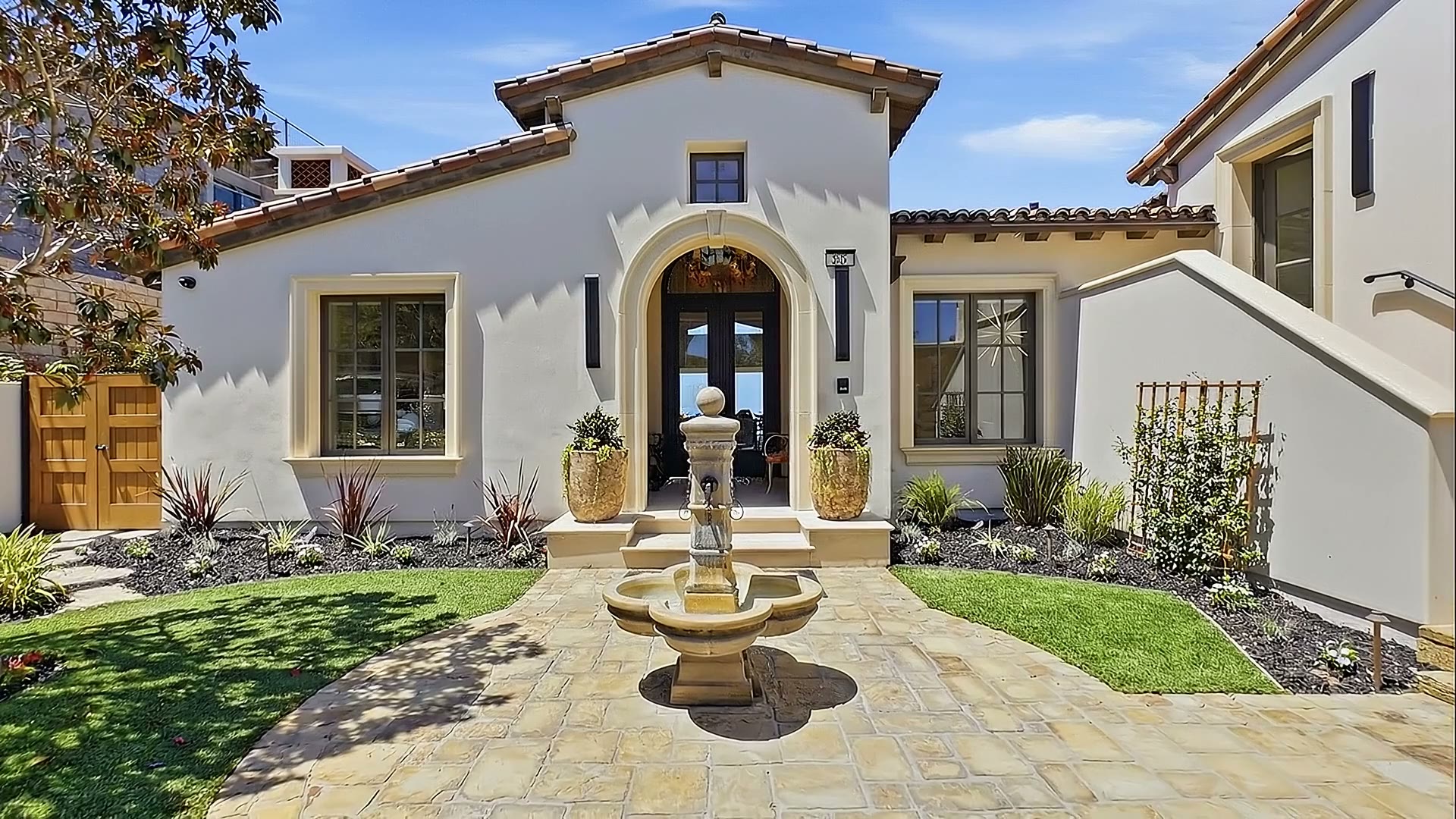 The entry courtyard with a stone fountain and an arched front door.