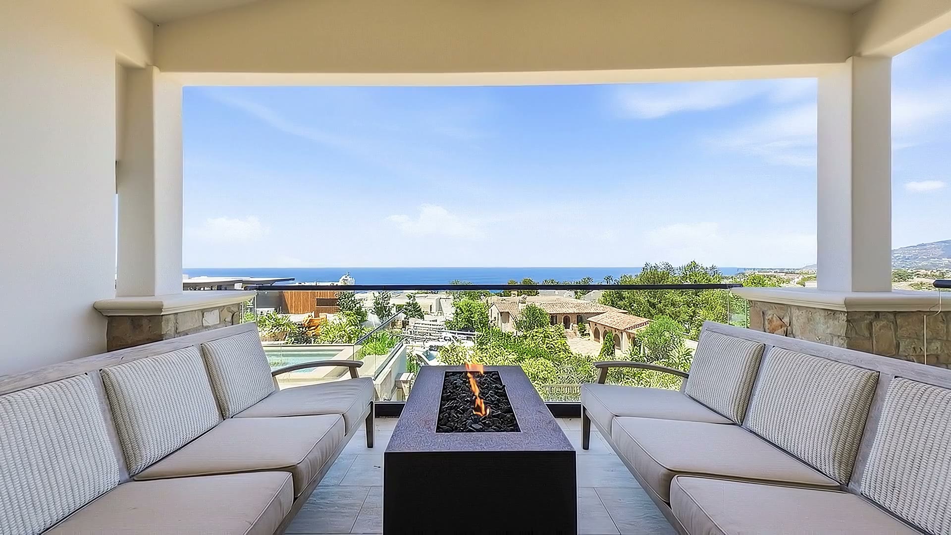 The covered upper loggia with a fire table and the ocean ahead.